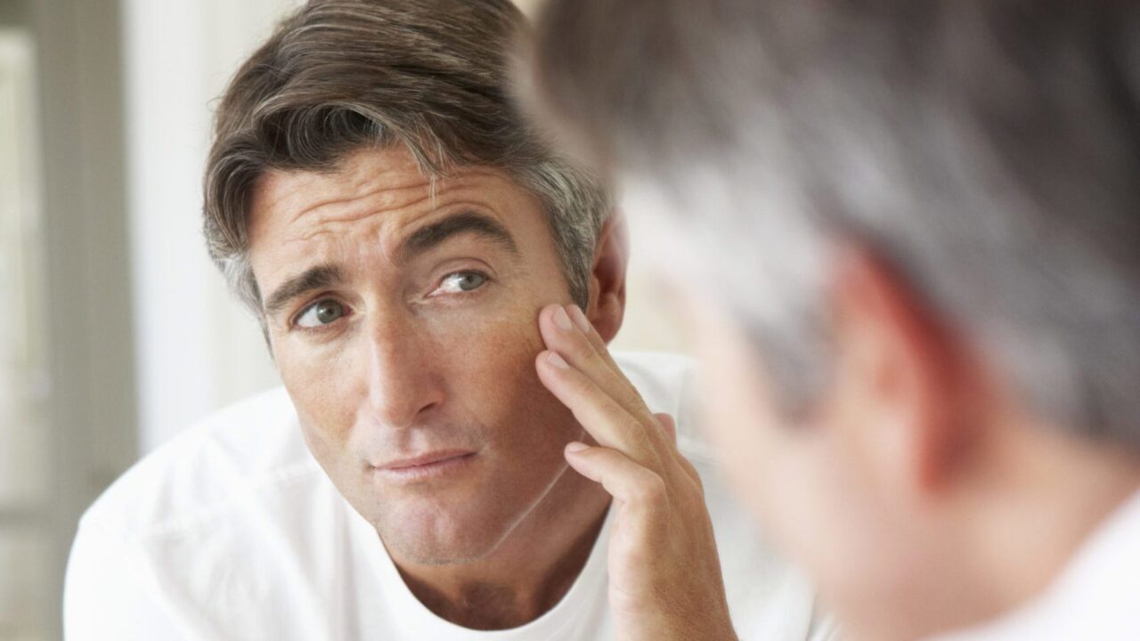 Man examining his face in a mirror