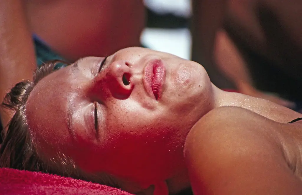 a woman sunbathing, ignoring skin cancer preventative measures